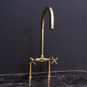 Unlacquered brass bridge faucet curved legs cross handles – installed in kitchen